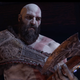 Kratos stares sadly at the axe he holds in his hands.